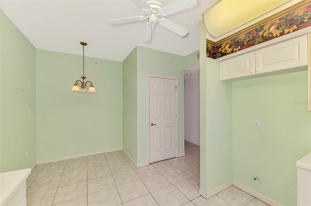 tiled spare room featuring ceiling fan with notable chandelier