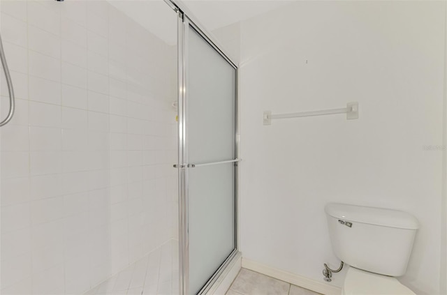 bathroom featuring tile patterned floors, toilet, and a shower with shower door