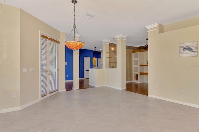 tiled empty room featuring crown molding and decorative columns