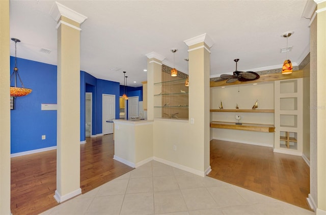 kitchen with decorative columns, ornamental molding, light tile patterned floors, ceiling fan, and built in shelves