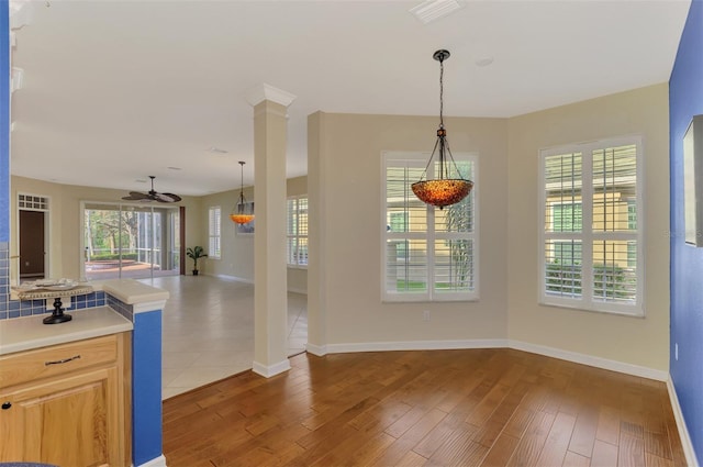 kitchen with ceiling fan, hanging light fixtures, wood-type flooring, light brown cabinetry, and ornate columns