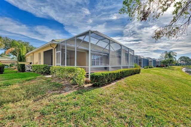 rear view of property featuring a lawn and glass enclosure