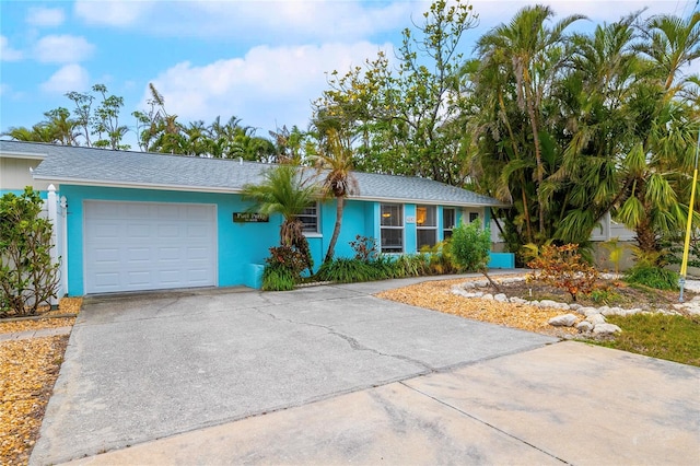 ranch-style house with a garage, concrete driveway, and stucco siding