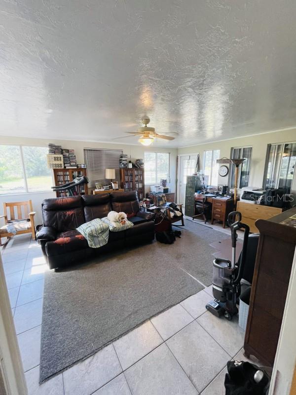 tiled living room featuring ceiling fan and a textured ceiling