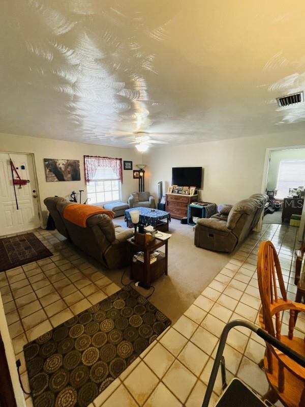 living room with ceiling fan and tile patterned floors