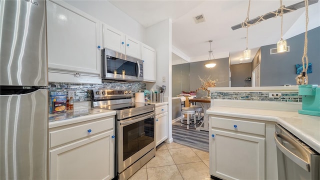 kitchen featuring light tile patterned flooring, tasteful backsplash, white cabinets, hanging light fixtures, and stainless steel appliances