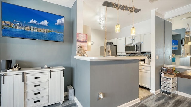 kitchen featuring pendant lighting, hardwood / wood-style flooring, white cabinetry, stainless steel appliances, and tasteful backsplash