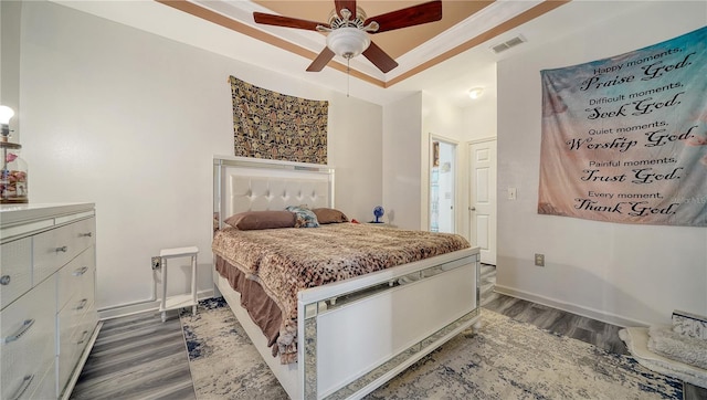 bedroom featuring dark hardwood / wood-style floors, ceiling fan, and a tray ceiling