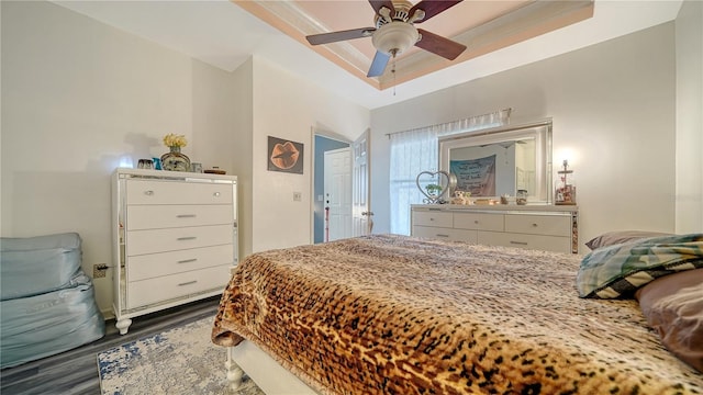 bedroom featuring ceiling fan, dark hardwood / wood-style flooring, and a tray ceiling