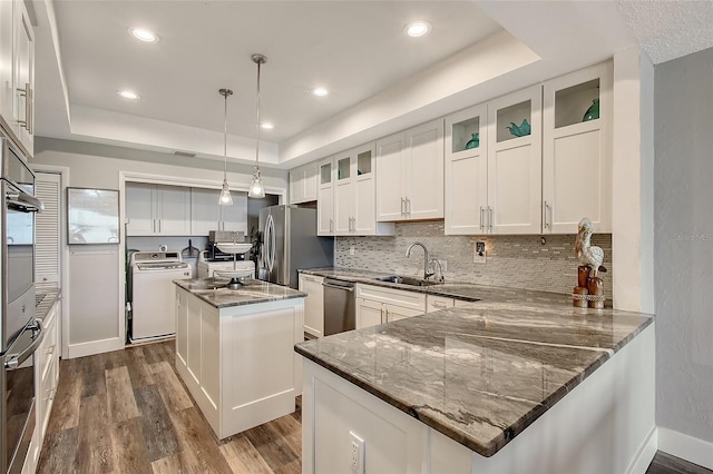 kitchen featuring appliances with stainless steel finishes, washer / dryer, a raised ceiling, and a kitchen island