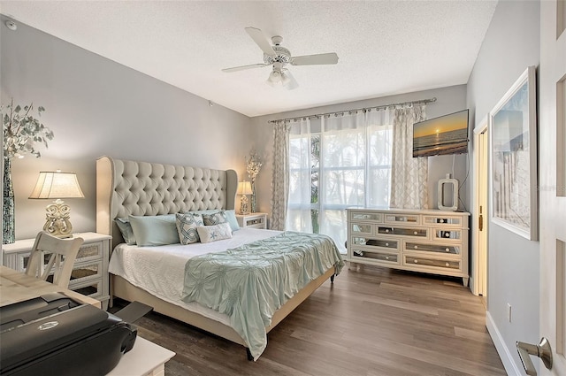 bedroom with ceiling fan, dark wood-type flooring, and a textured ceiling