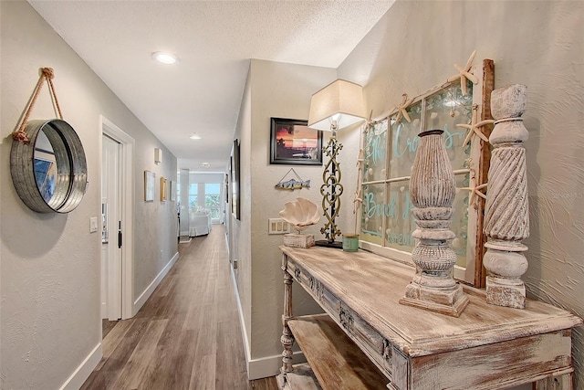 hallway with hardwood / wood-style floors and a textured ceiling