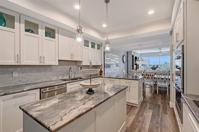 kitchen with a kitchen island, decorative light fixtures, dishwasher, sink, and white cabinets