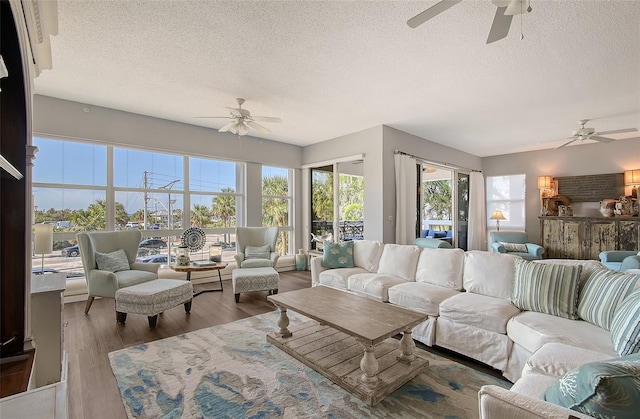 living room featuring hardwood / wood-style floors, a textured ceiling, and ceiling fan