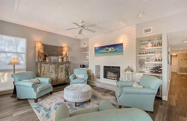 living room featuring wood-type flooring, ceiling fan, and a textured ceiling