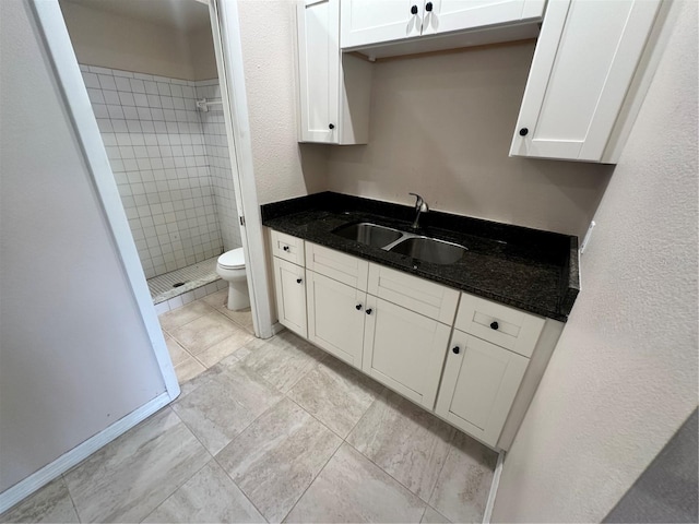 bathroom featuring a tile shower, toilet, tile patterned flooring, and vanity