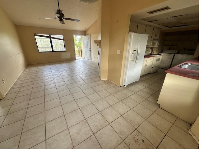 kitchen with white appliances, white cabinets, washer and clothes dryer, ceiling fan, and light tile patterned flooring