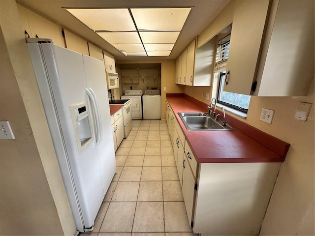 kitchen with sink, white appliances, light tile patterned flooring, and independent washer and dryer