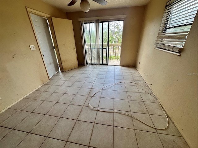 tiled spare room featuring a textured ceiling and ceiling fan