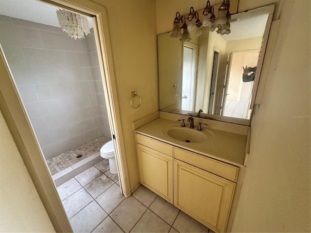 bathroom featuring toilet, vanity, a tile shower, and tile patterned flooring