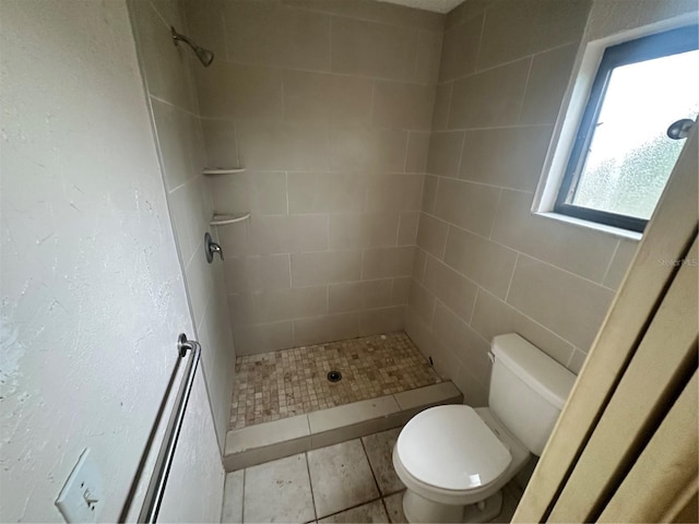 bathroom featuring tile patterned floors, toilet, and a tile shower