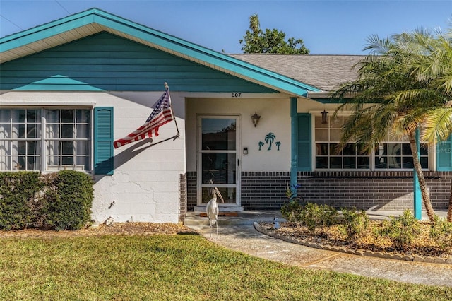 807 62nd St W, Bradenton, FL 34209 - view of front of house featuring brick siding, a front lawn, and a shingled roof