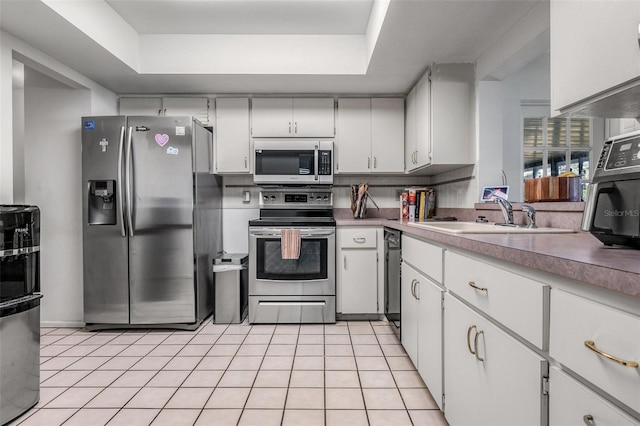807 62nd St W, Bradenton, FL 34209 - kitchen featuring stainless steel appliances, a sink, a tray ceiling, and light tile patterned floors