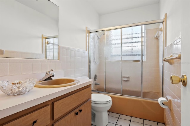 807 62nd St W, Bradenton, FL 34209 - bathroom with vanity, toilet, tile patterned flooring, bath / shower combo with glass door, and tile walls