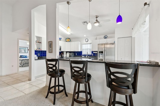 kitchen with pendant lighting, ceiling fan, white cabinets, decorative backsplash, and stainless steel appliances