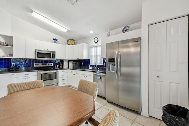 kitchen featuring sink, white cabinetry, appliances with stainless steel finishes, and lofted ceiling