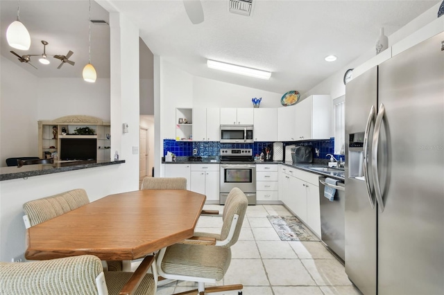 kitchen with decorative light fixtures, white cabinets, decorative backsplash, and appliances with stainless steel finishes