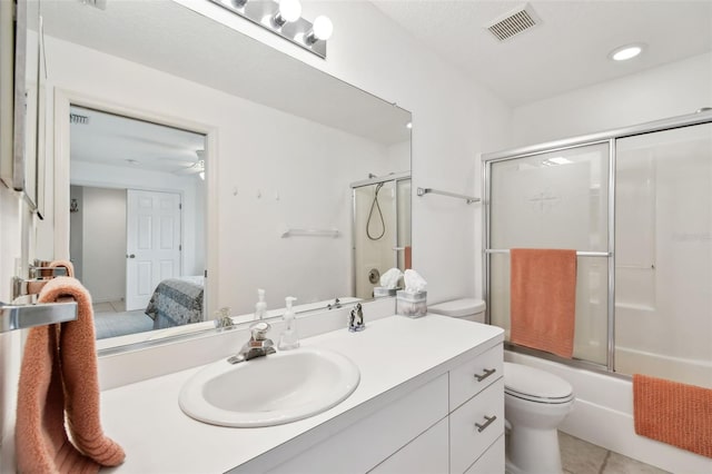 full bathroom featuring toilet, bath / shower combo with glass door, tile patterned floors, vanity, and ceiling fan