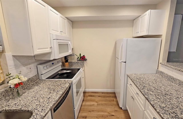 kitchen featuring white appliances, light stone counters, light hardwood / wood-style floors, white cabinets, and decorative backsplash