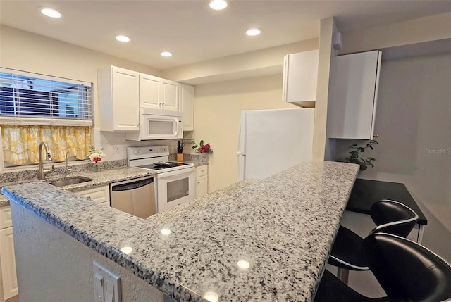 kitchen featuring white cabinetry, white appliances, sink, and light stone counters