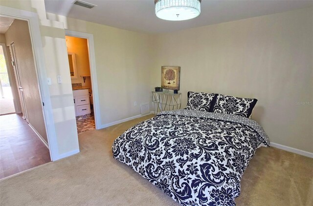 bedroom featuring ensuite bathroom and carpet