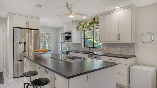 kitchen with white cabinetry, sink, a kitchen island, and appliances with stainless steel finishes