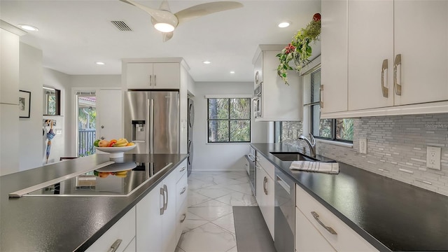 kitchen featuring tasteful backsplash, white cabinetry, appliances with stainless steel finishes, and sink