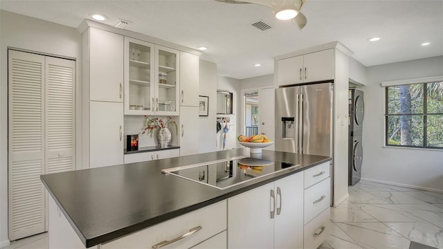 kitchen with white cabinetry, high end refrigerator, black electric cooktop, ceiling fan, and stacked washing maching and dryer