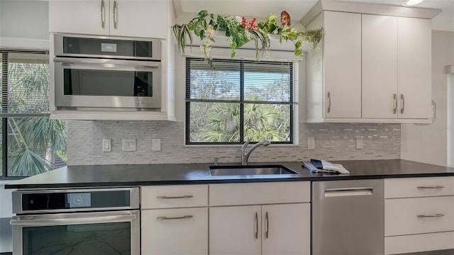 kitchen featuring stainless steel appliances, sink, decorative backsplash, and white cabinets