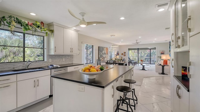 kitchen with sink, a kitchen bar, white cabinets, and a kitchen island