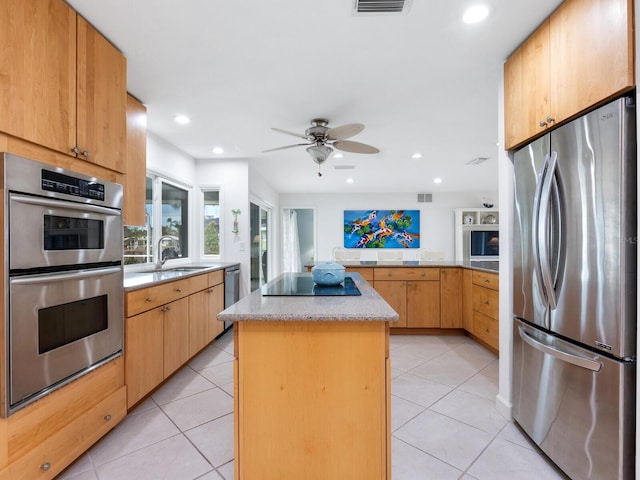 kitchen with light tile patterned flooring, stainless steel appliances, sink, and a kitchen island