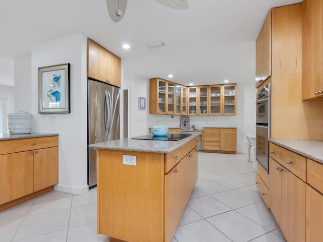 kitchen with light tile patterned floors, light stone countertops, a center island, and appliances with stainless steel finishes