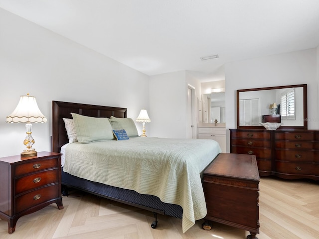 bedroom featuring connected bathroom and light parquet flooring