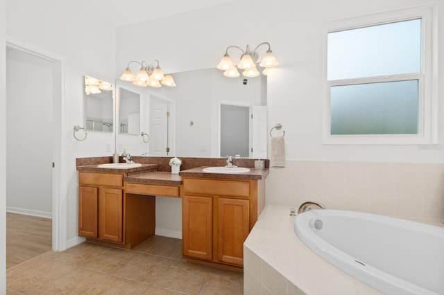 bathroom with tiled bath, vanity, a chandelier, and tile patterned flooring