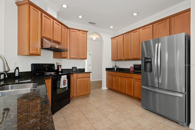 kitchen with appliances with stainless steel finishes, light tile patterned flooring, dark stone counters, crown molding, and sink