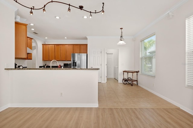 kitchen featuring sink, crown molding, hanging light fixtures, light wood-type flooring, and appliances with stainless steel finishes