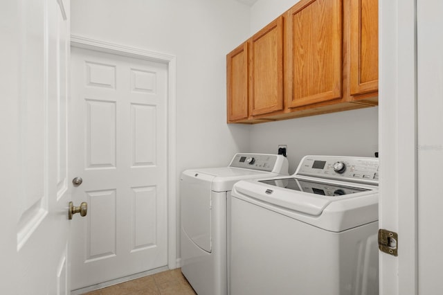 washroom featuring washing machine and dryer, cabinets, and light tile patterned floors