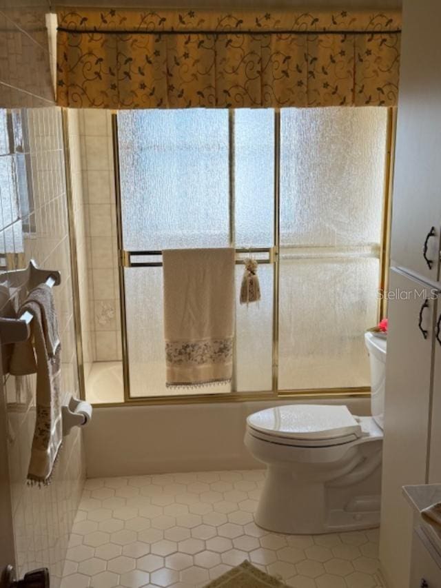 full bathroom with tile patterned floors, combined bath / shower with glass door, vanity, and toilet