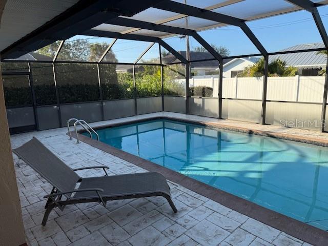 view of pool featuring glass enclosure and a patio