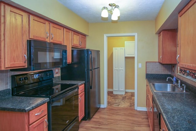 kitchen with sink, a chandelier, decorative backsplash, black appliances, and light hardwood / wood-style flooring